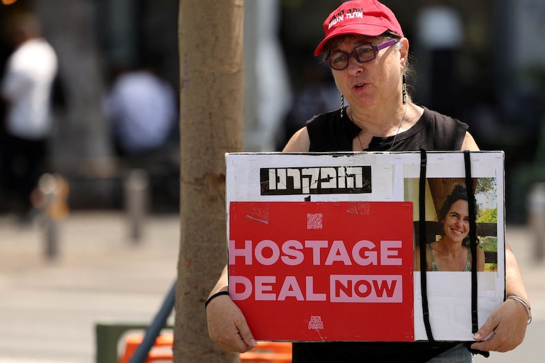 A woman holds a poster with a picture of Carmel Gat, in Tel Aviv